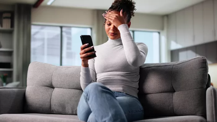 stressed woman sitting on couch viewing phone