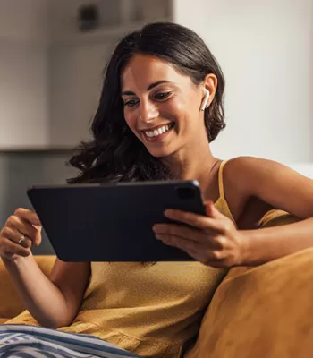 happy woman using iPad on couch