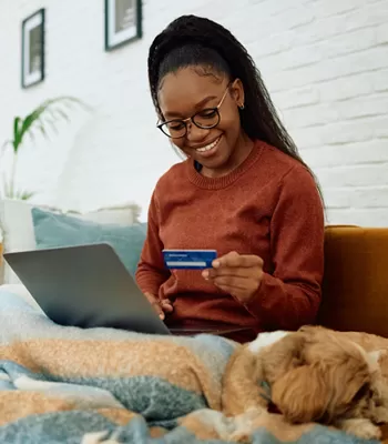 young woman on couch using visa credit card