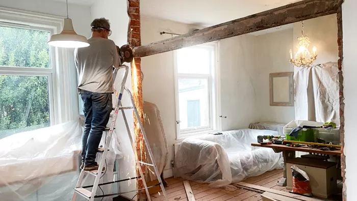 man demoing inside of home with saw