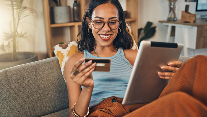 women on a couch using her debit card