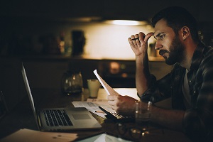 man sitting at computer reviewing finances
