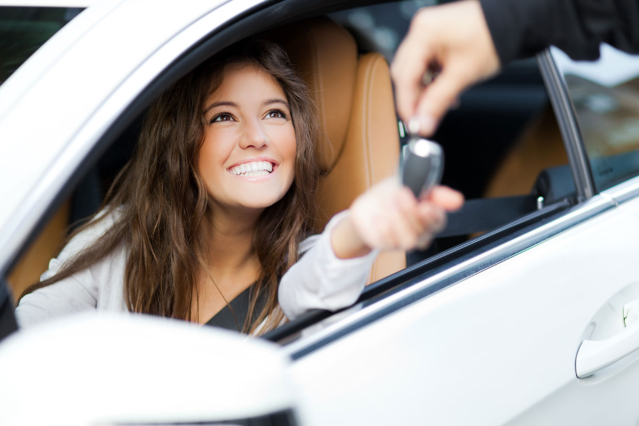 young woman getting keys to new car